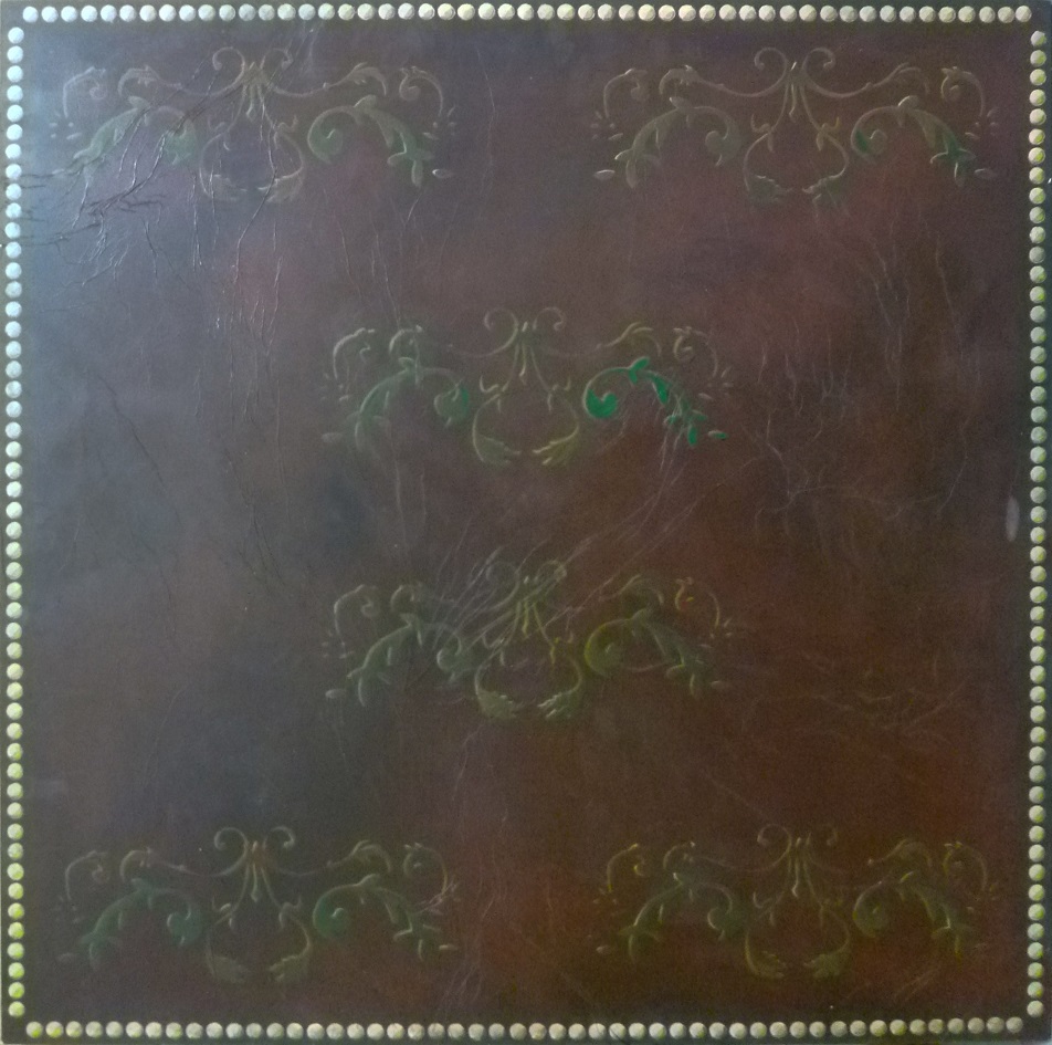 une peinture marron imitant du cuir avec des dessins faits au pochoir et des clous dorés en trompe l'oeil tout autour