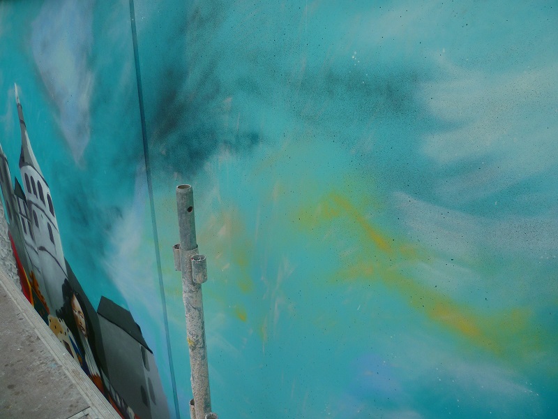 détail d'une fresque murale à la bombe, des couleurs se mélangent dans le ciel