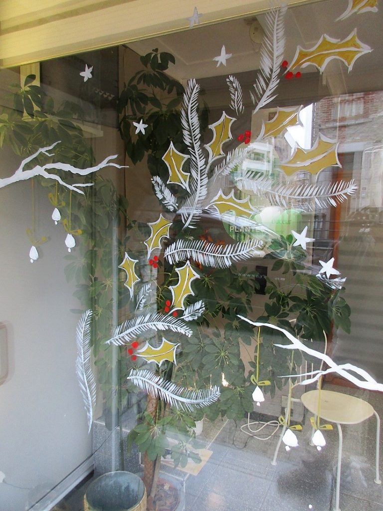 petites branches de houx et sapin avec étoiles en blanc et ocre jaune peintes sur vitrine